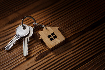 House keys with house shaped keychain on wooden background