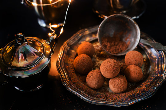 vegan chocolate truffles - dessert for the New Year's Eve, carnival against the background of silverware, elegant, vintage. On a dark background.
