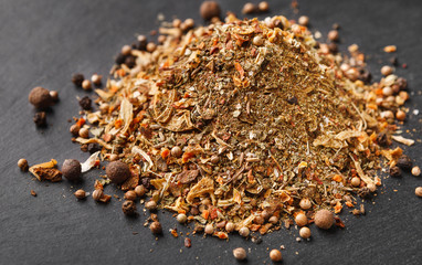 Mix of spices, herbs and peppercorns on dark board