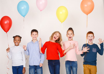 Happy children with colourful balloons over wall
