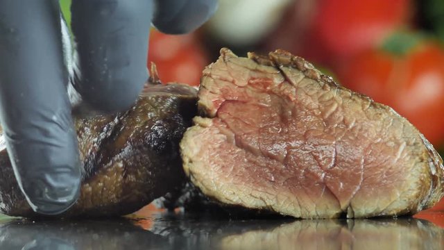 Sliced entrecote medium roasting chef in black gloves puts on a platter for further roasting