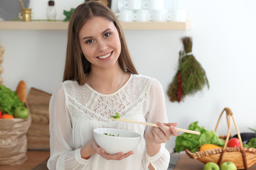 Young happy woman cooking in the kitchen. Healthy meal, lifestyle and culinary concepts. Good morning begins with fresh salad