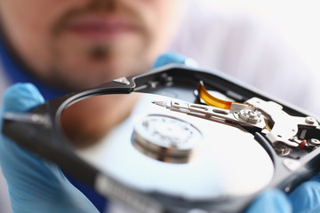 A male repairman wearing blue gloves is holding