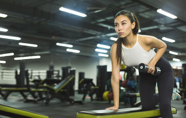 Fototapeta na wymiar Slim girl warming up with weights in health club