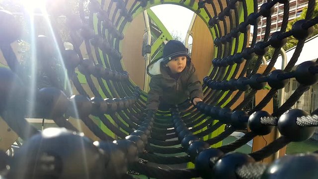 Baby Boy Crawling Through A Rope Tunnel Bridge