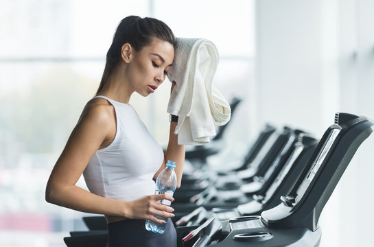 Woman tired and having rest after running on treadmill