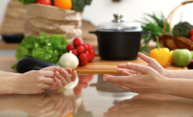Closeup of human hands discussing something while cooking in kitchen. Women talking about menu. Family dinner, friendship and lifestyle concept