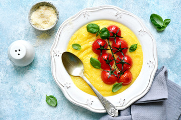 Traditional italian dish polenta with parmesan cheese and grilled tomato.