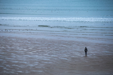 Fototapeta na wymiar homme seul sur la plage immense perdu dans ses pensées