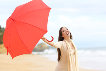 Candid woman playing with a red umbrella on the beach