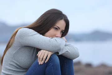 Sad girl looking away alone on the beach