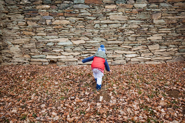 Fototapeta na wymiar Kind klettert zu Steinmauer. Kid climbing to stonewall.