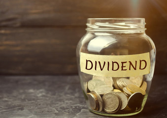 Glass jar with the word Dividend. A dividend is a payment made by a corporation to its shareholders...