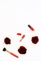 Obraz na płótnie Canvas Makeup cosmetic accessories products in red color and red flowers roses on white background. Top view. Flat lay. Copy space