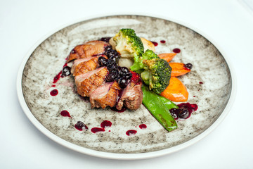 Dish with fried meat and vegetables on a white background