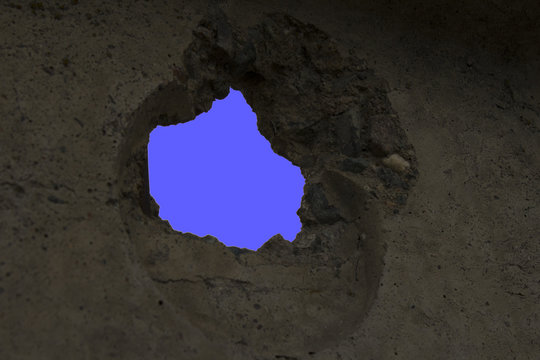 blue sky through a hole in the concrete wall