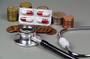 Piles de pièces, stéthoscope et plaquette de médicament