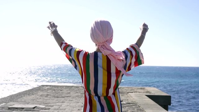Woman with pink headscarf in the beach, has cancer