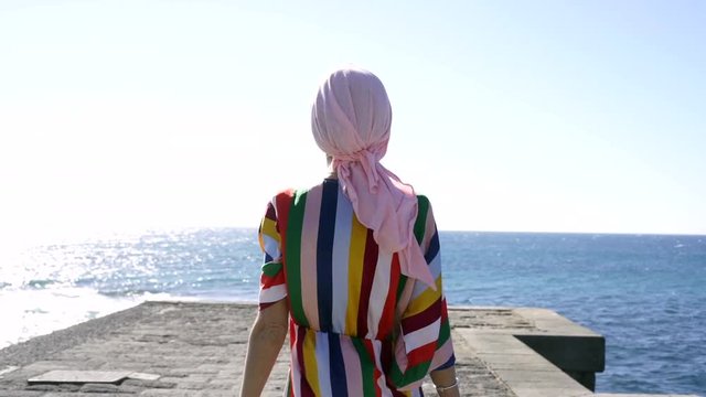 Woman with pink headscarf in the beach, has cancer