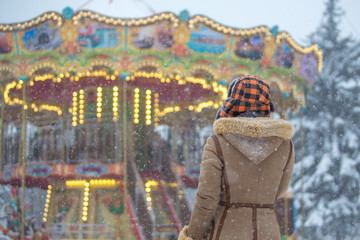 Obraz na płótnie Canvas Woman looks at the Victorian carousel on a snowy day