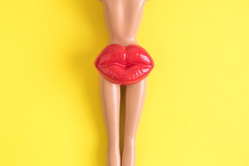 Doll with lips on bottom isolated on yellow abstract.