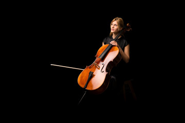 Young girl playing the cello on isolated black background