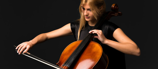 Young girl playing the cello on isolated black background