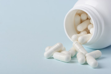 Drugs in bottle spill on blue background with copy-space