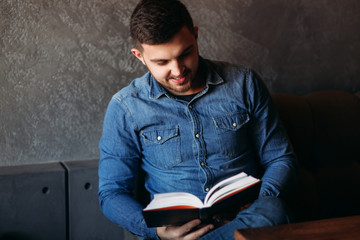 Obraz premium Student read book in cafe. Study and education. Young man spend time in cafe