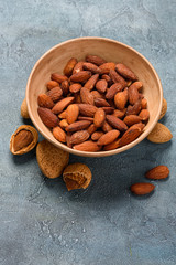 Salted fried almonds in a bowl with almond nuts in shells
