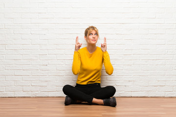 Young girl sitting on the floor with fingers crossing and wishing the best