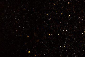 Shiny golden glitter particles falling on black background