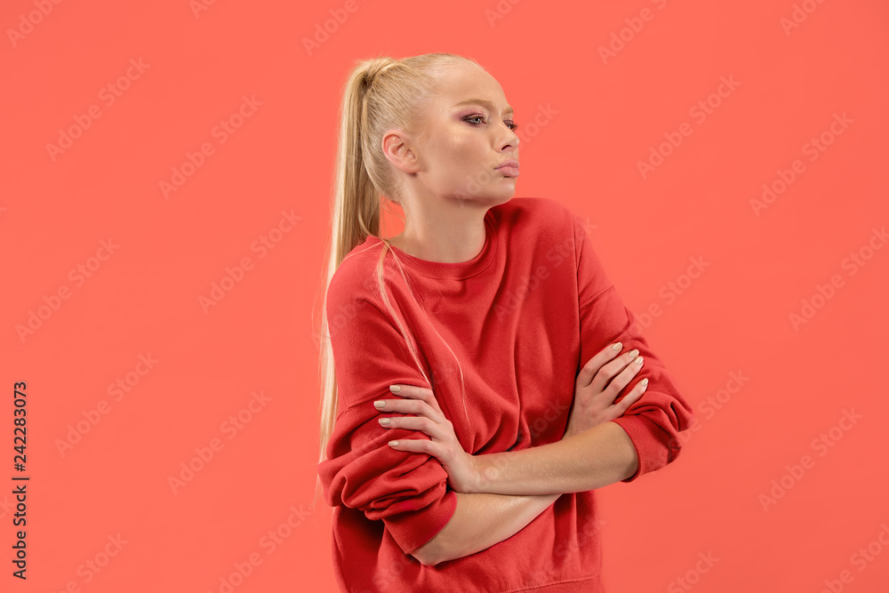 Wall mural serious business woman standing, looking at camera isolated on trendy coral studio background. beaut