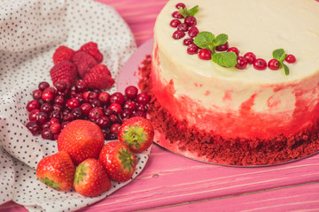 close up of white cake decorated with red currants and mint leaves near other fruits