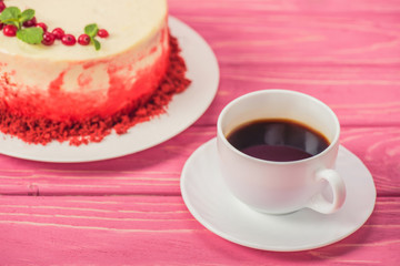 close up of cake decorated with currants and mint leaves near cup of coffee