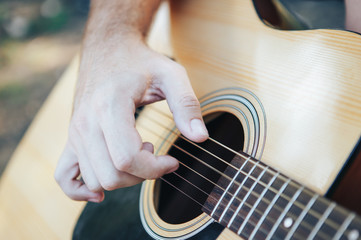 Fototapeta premium Close up of man hand playing guitar. Man playing guitar. Playing on acoustic guitar outdoor
