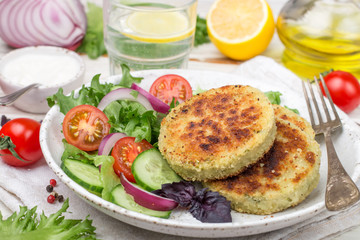 Cutlets (patties ) from white fish (Pollock, cod, perch, pike) in a Plate with lettuce, tomato and...