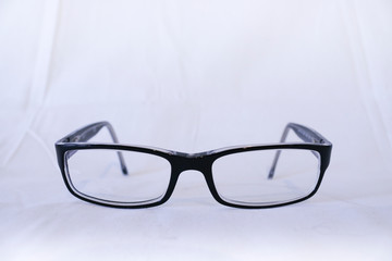 Primo piano di un paio di occhiali da vista neri, sfondo bianco, oggetti di uso quotidiano