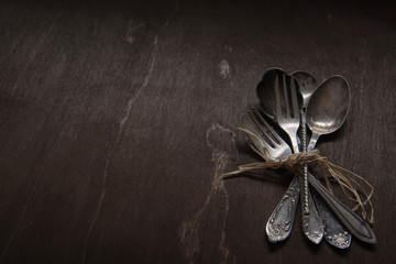 Vintage silver spoons, forks and knife on vintage black background. Low-key