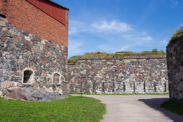 Fototapeta na wymiar The old granite walls of the historic fortifications on Suomenlinna Forte Island are overgrown with grass in summer. Suomenlinna Island in the Gulf of Finland are tourist attractions.