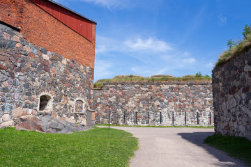 Fototapeta na wymiar The old granite walls of the historic fortifications on Suomenlinna Forte Island are overgrown with grass in summer. Suomenlinna Island in the Gulf of Finland are tourist attractions.