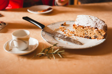 Close-up of cup of coffee and amaretto cake wit rosemary branch