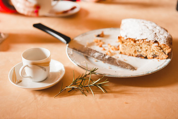 Close-up of cup of coffee and amaretto cake wit rosemary branch