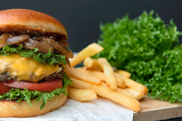 beef burger and french fries on table with black background.