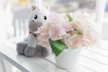 horse doll behind flower bouquet at top of white desk
