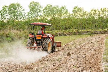Naklejka premium Tractor working plows a field on the farm for planting