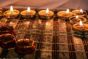 Sweets, milk candies and dark chocolate broken, on the background of lights, candles. Warm, soft and pleasant shade. Dessert is gentle and natural in a romantic home environment.