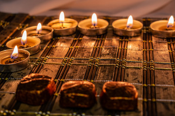 Sweets, milk candies and dark chocolate broken, on the background of lights, candles. Warm, soft and pleasant shade. Dessert is gentle and natural in a romantic home environment.