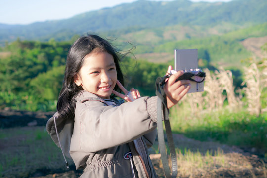 A little girl is taking a camera for selfie