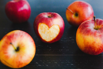 group of red apples with different tones on dark wooden table